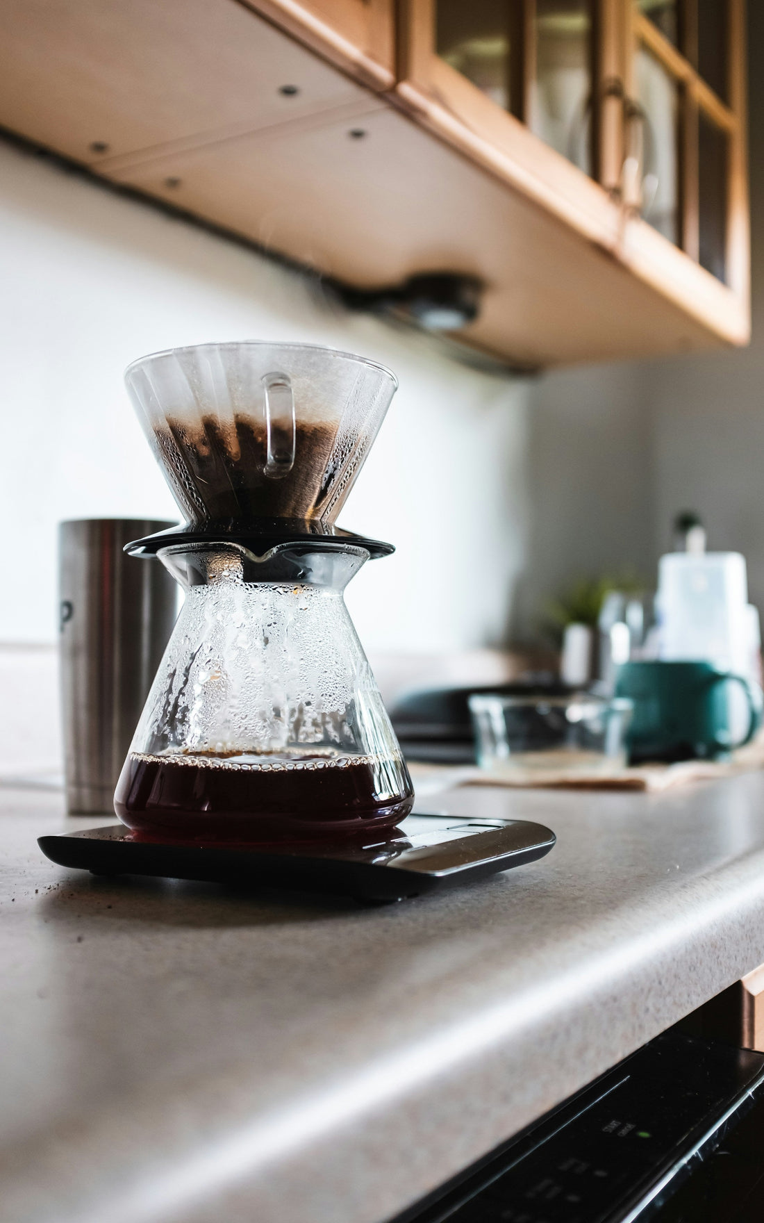 Mit Kaffee gefüllter Coffee Server mit Dripper auf Waage auf einer Küchenarbeitsplatte