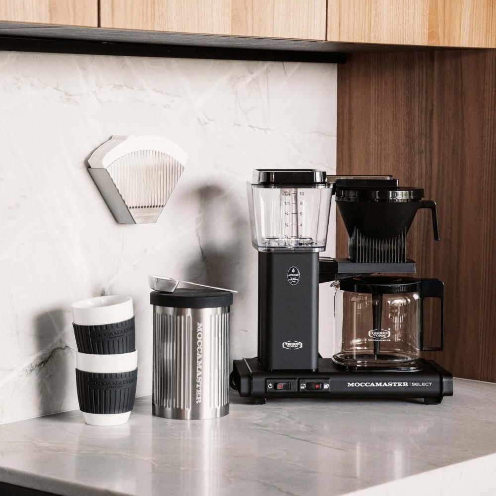 Moccamaster Filterhalter, Edelstahl, Filter Nr. 4, mit Moccamaster Dose und Löffel neben Moccamaster KBG Select Maschine