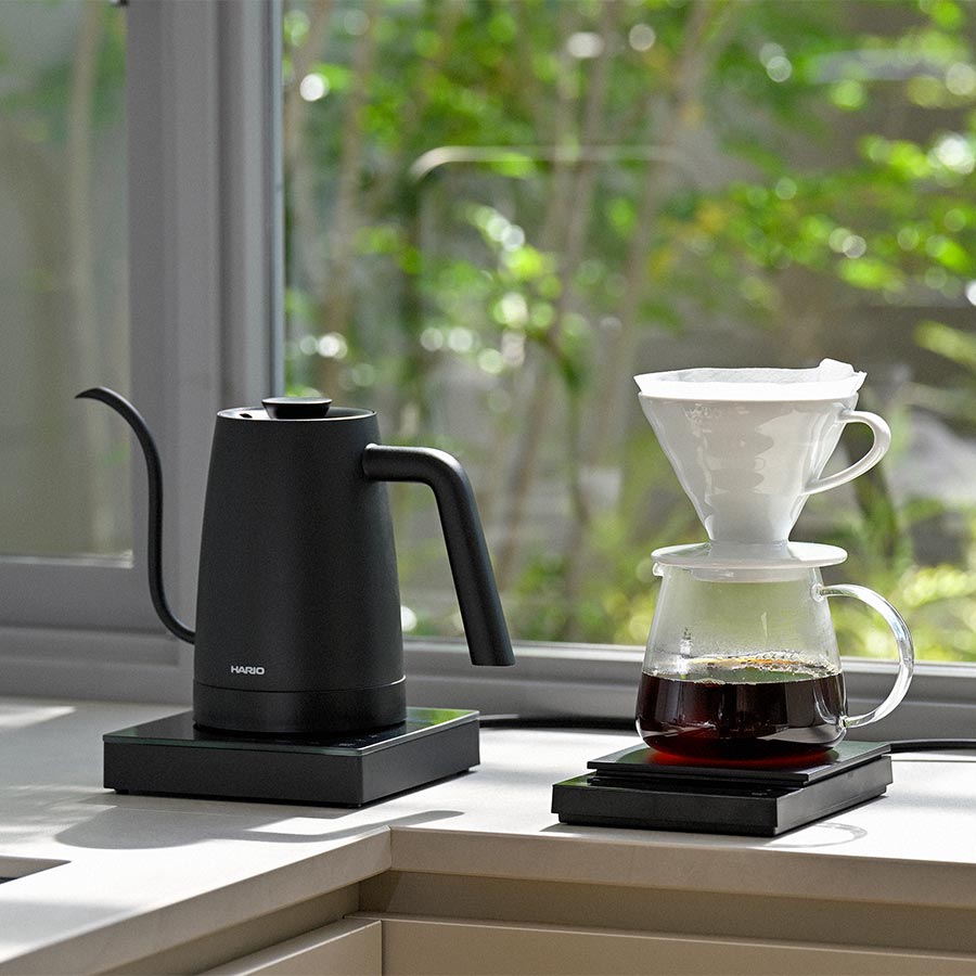 Hario Lyra elektrischer Wasserkocher 0,8 l Schwarz neben Hario Polaris Scale mit Kanne und V60 Dripper